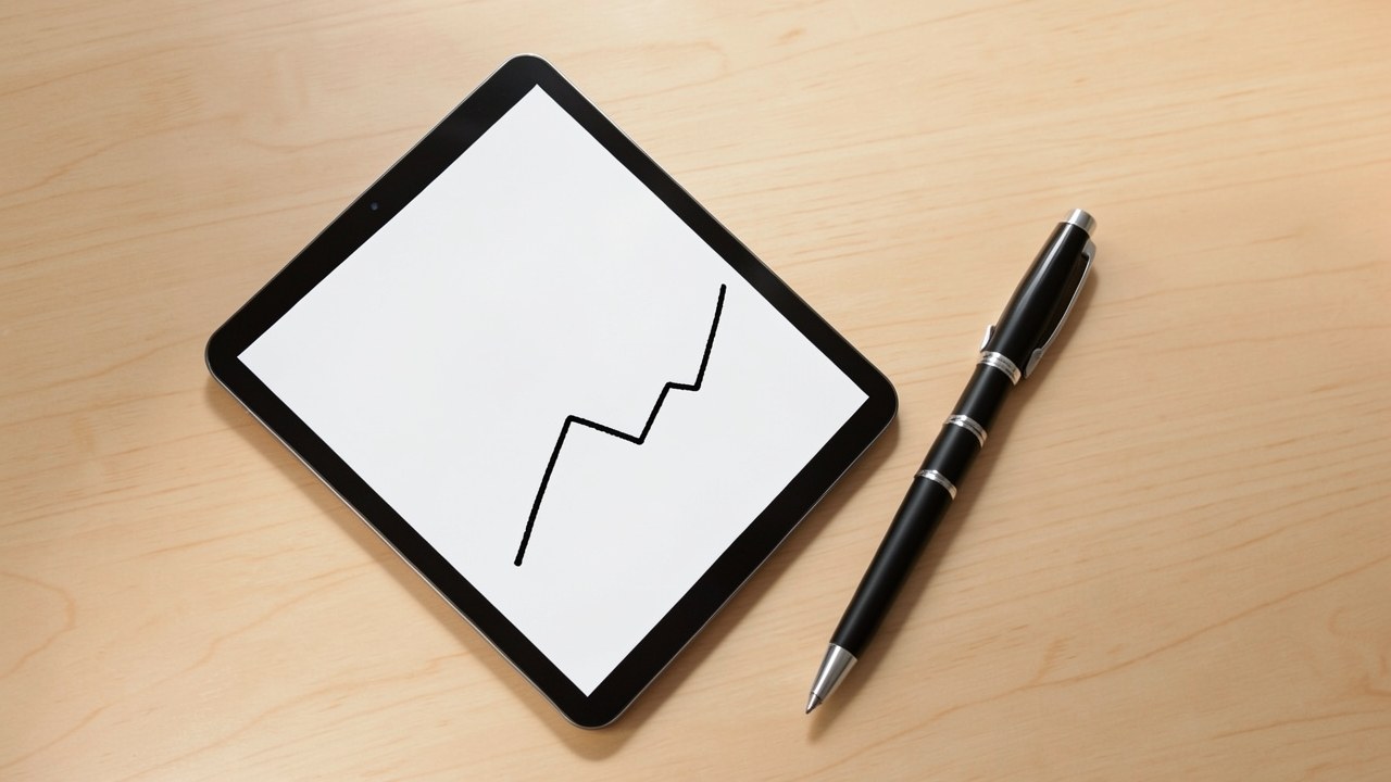 A graph on a tablet rising and falling, with a pen lying next to it on a desk.